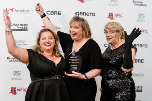 Three women holding an award at an award show