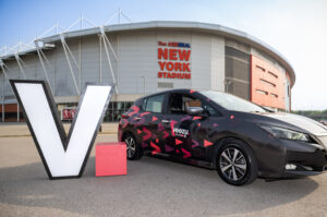 A white 'V' and a black car in front of a building