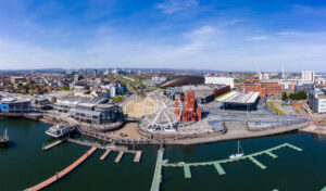 Panoramic aerial view of Cardiff Bay on a sunny day with the city centre in the background.