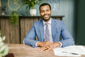 Smiling Man in Blue Suit Sitting by the Table