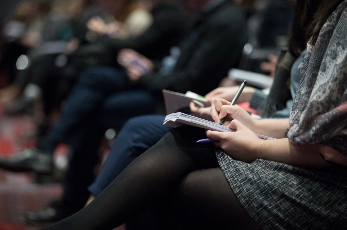 Close up image of a woman making notes at a business event.